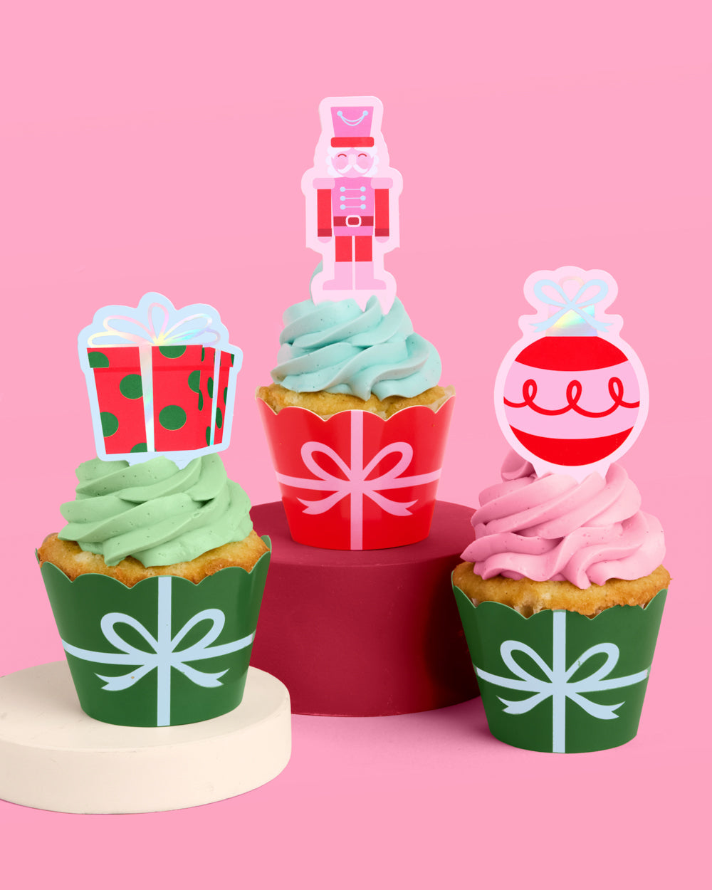 Decorative cupcakes with festive toppers on a pink background