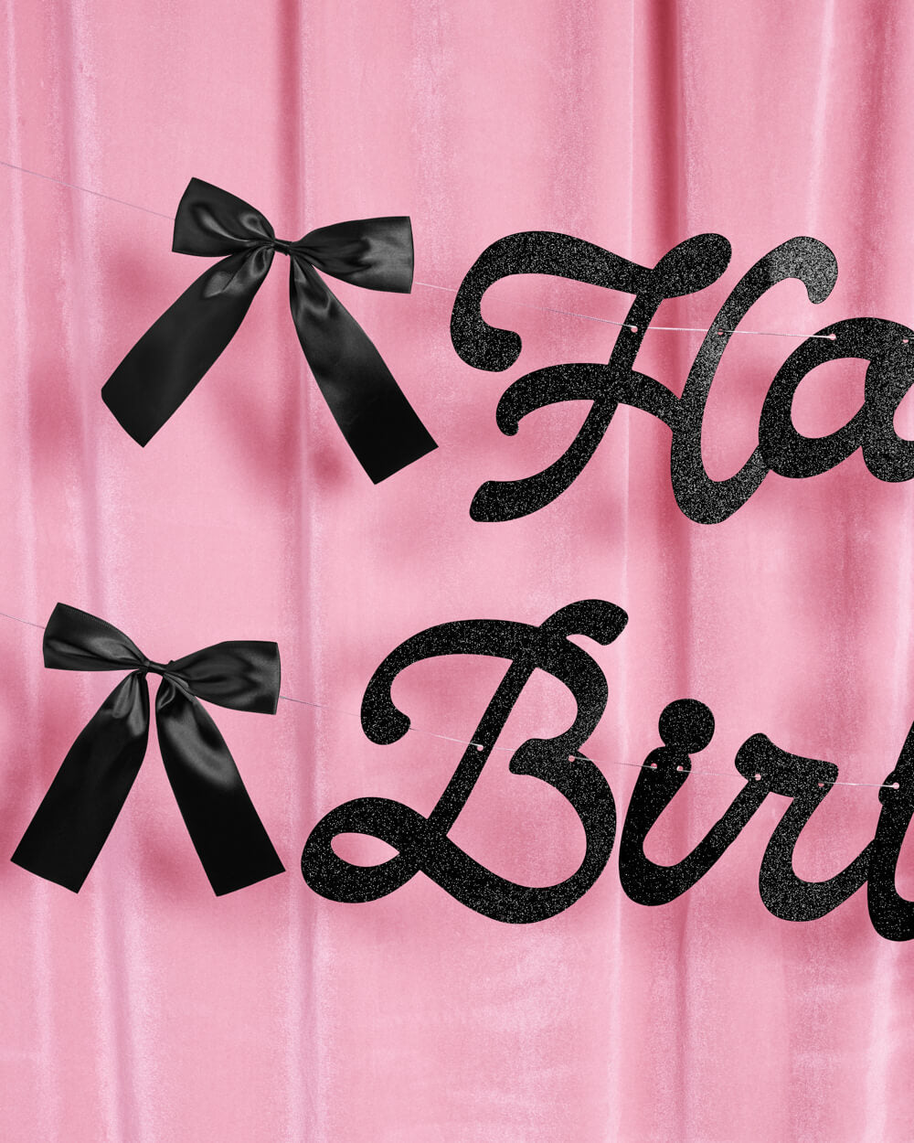 Happy Birthday text with black ribbons on a pink background