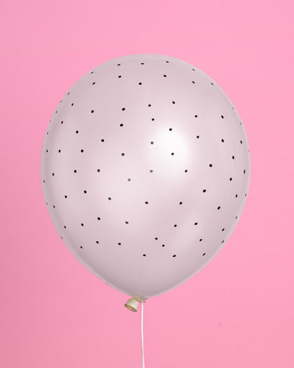 White balloon with black dots on a pink background