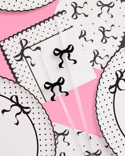 Patterned fabric with black bows and white polka dots on a pink background