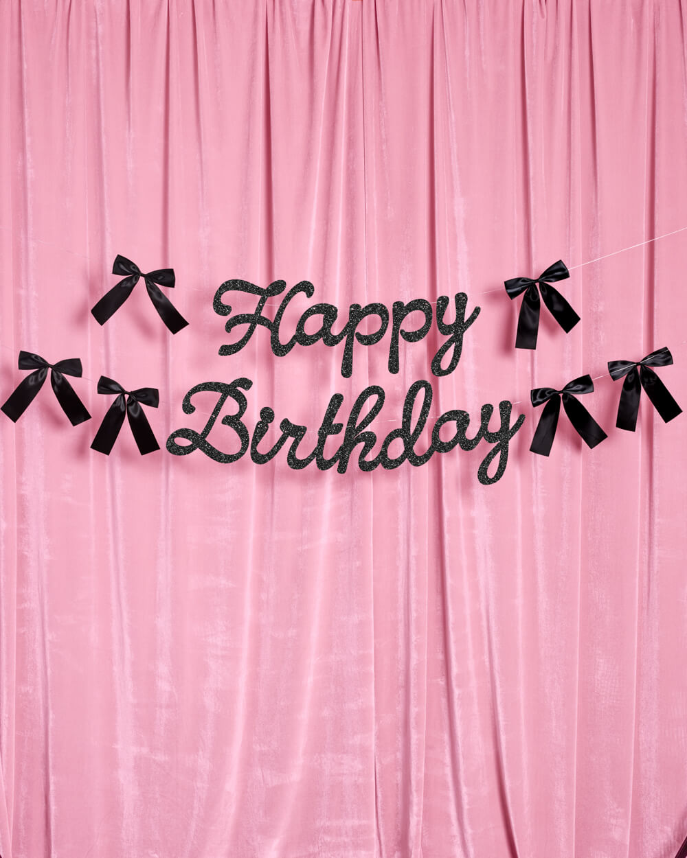 Black 'Happy Birthday' banner on a pink curtain background