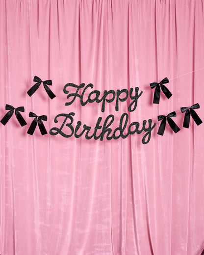 Black 'Happy Birthday' banner on a pink curtain background