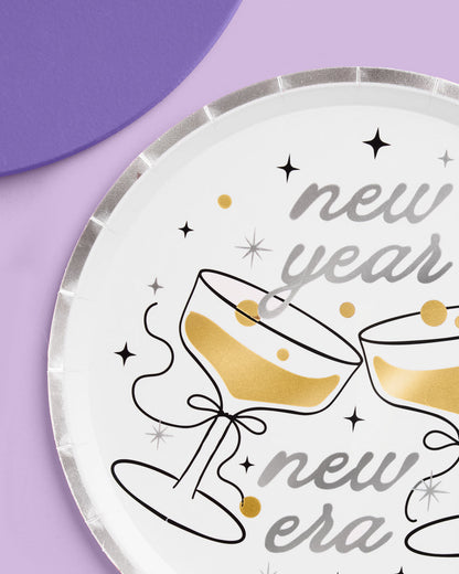 New Year's Eve paper plate with champagne glasses and text on a purple background