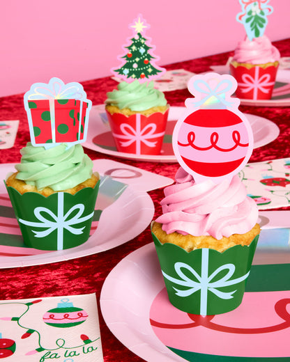 Christmas-themed cupcakes with decorative toppers on a festive table setting.