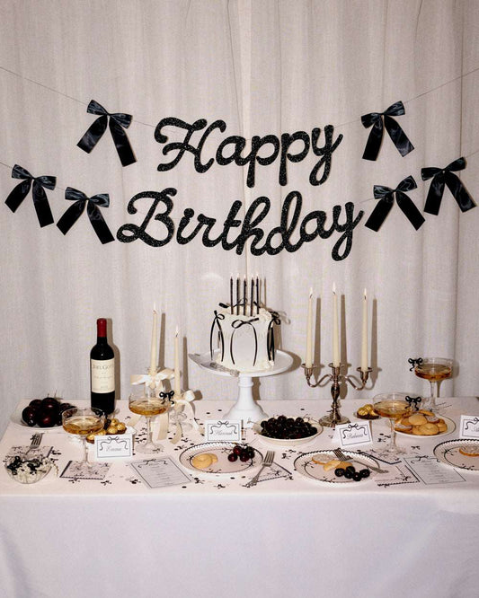 Decorated birthday table with cake, candles, and 'Happy Birthday' banner.