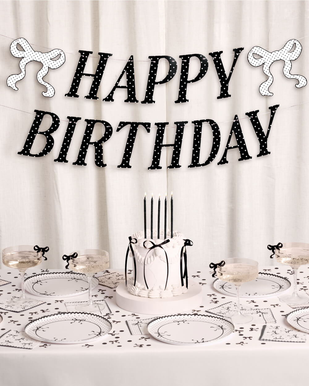 Birthday table setting with 'Happy Birthday' banner and cake.