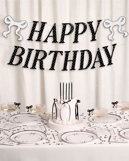 Birthday table setting with 'Happy Birthday' banner and cake.