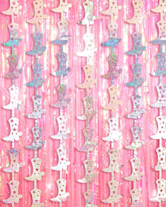 Holographic silver cowgirl boot garlands hanging in front of a pink metallic fringe foil curtain.