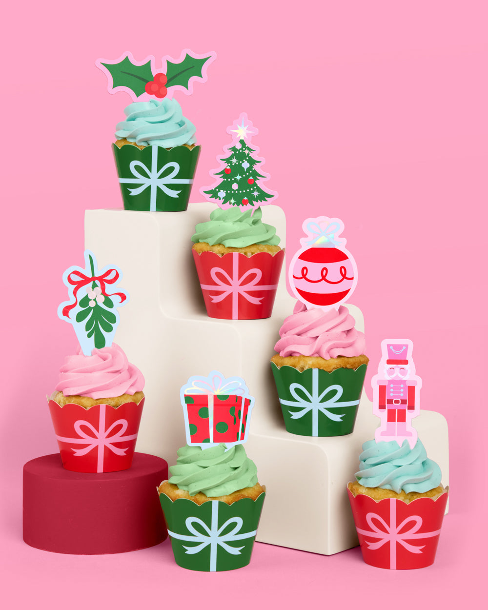 Decorative Christmas-themed cupcake toppers on a pink background