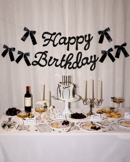 Decorated birthday table with cake, candles, and 'Happy Birthday' banner.