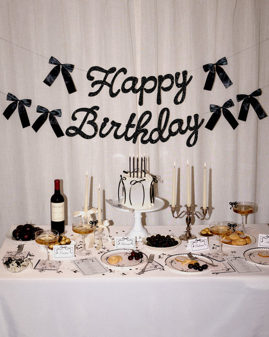 Decorated birthday table with cake, candles, and 'Happy Birthday' banner.