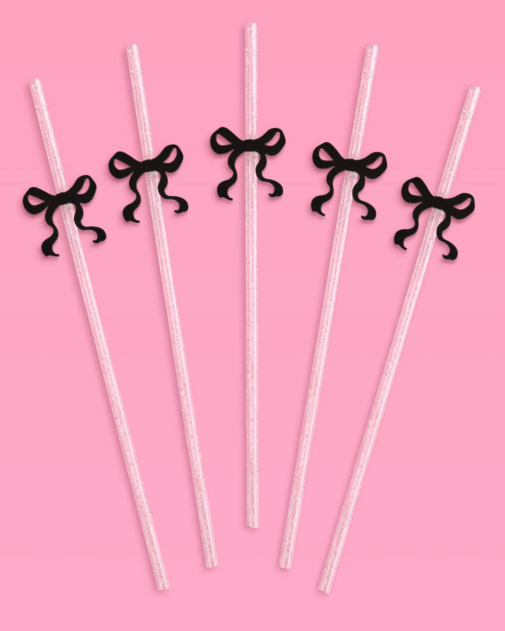 Clear straws with black ribbons on a pink background