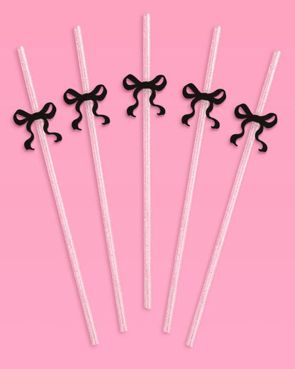Clear straws with black ribbons on a pink background