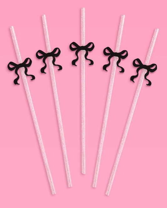 Clear straws with black ribbons on a pink background
