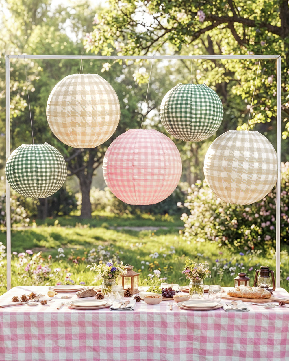 Decorative paper lanterns hanging above a table set outdoors with a checkered tablecloth.