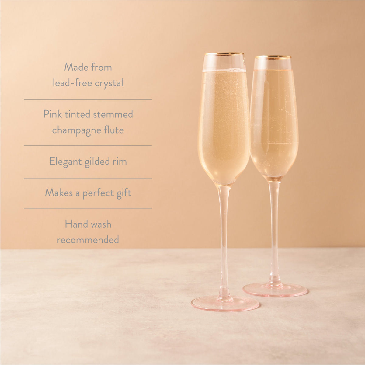 Two pink-tinted stemmed champagne flutes with champagne on a beige background, featuring text about the product.
