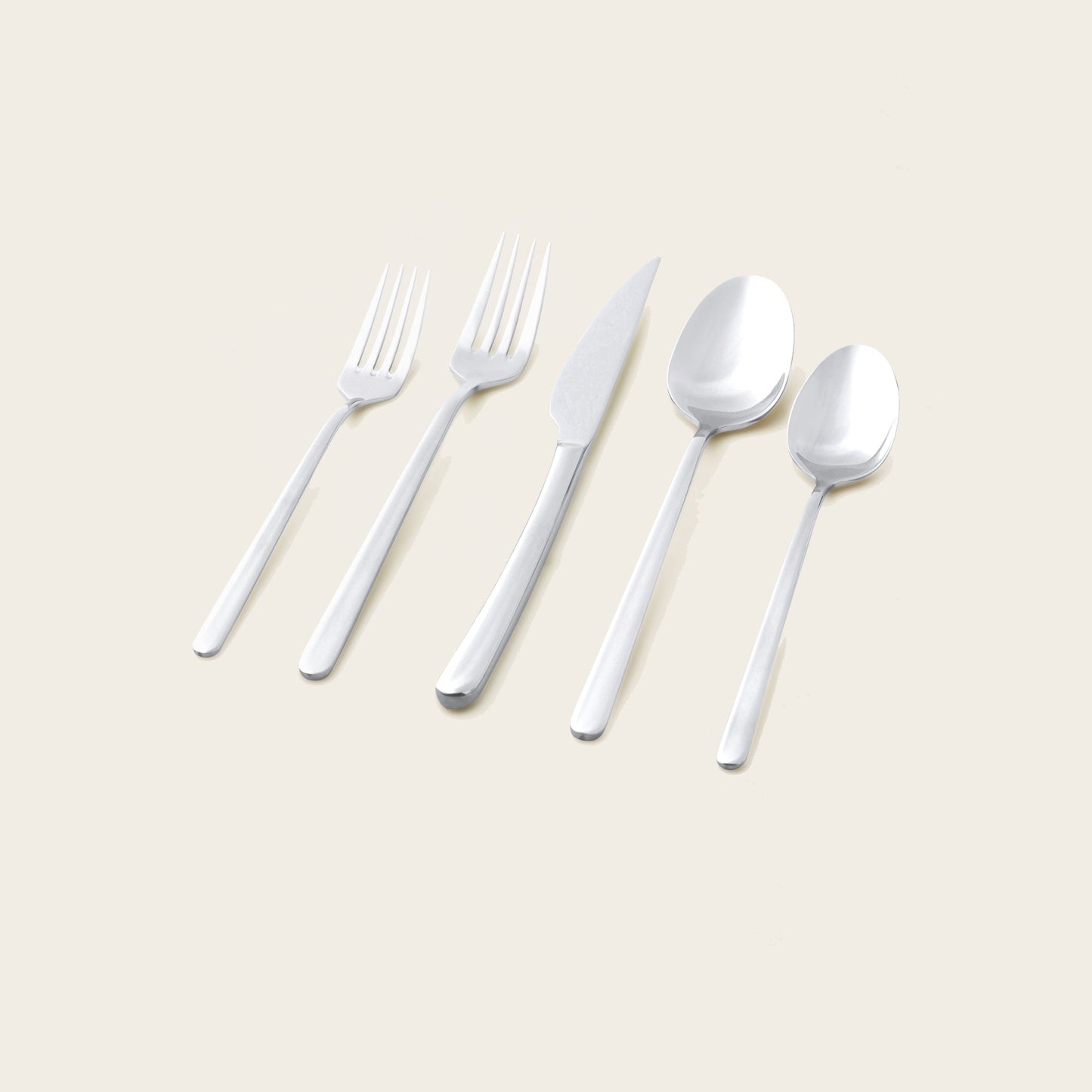Set of silver cutlery including forks, a knife, and spoons on a beige background