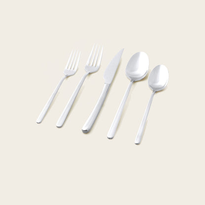 Set of silver cutlery including forks, a knife, and spoons on a beige background