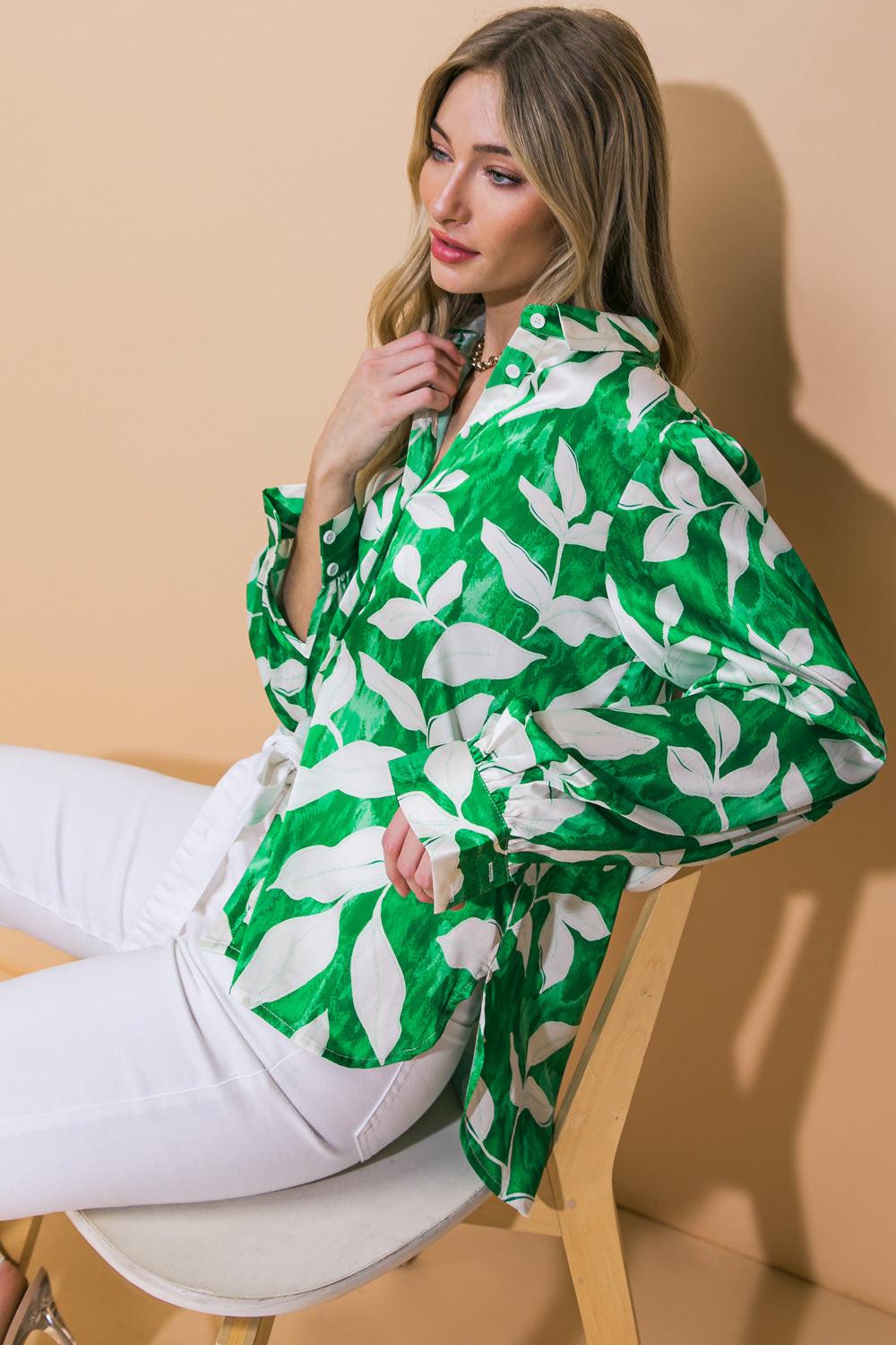 Woman wearing a green and white patterned blouse sitting on a chair against a beige background