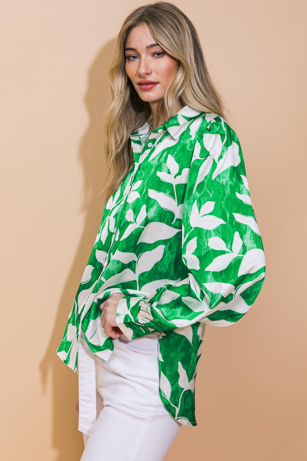 Woman wearing a green and white leaf-patterned blouse against a beige background