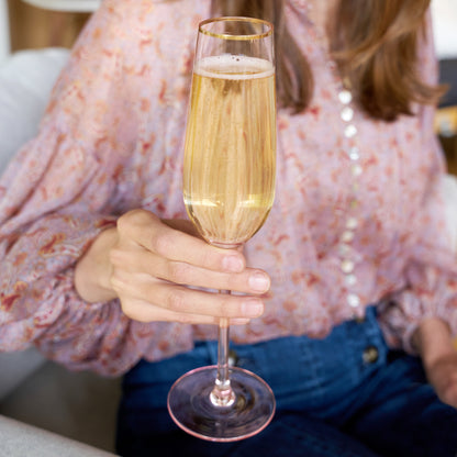 Person holding a glass of champagne with a blurred background