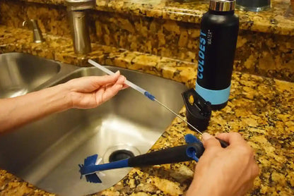 Person using a water filter on a kitchen sink with a Colossus Water bottle in the background.