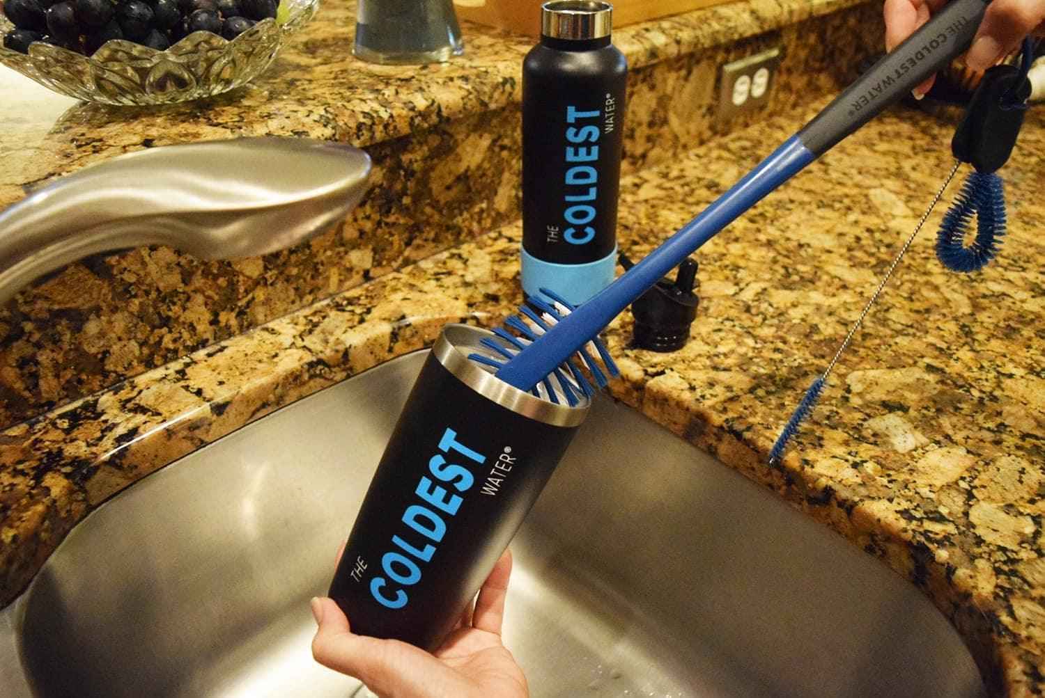 Coldest branded water bottles and brush on a kitchen sink with granite countertop.