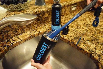 Coldest branded water bottles and brush on a kitchen sink with granite countertop.