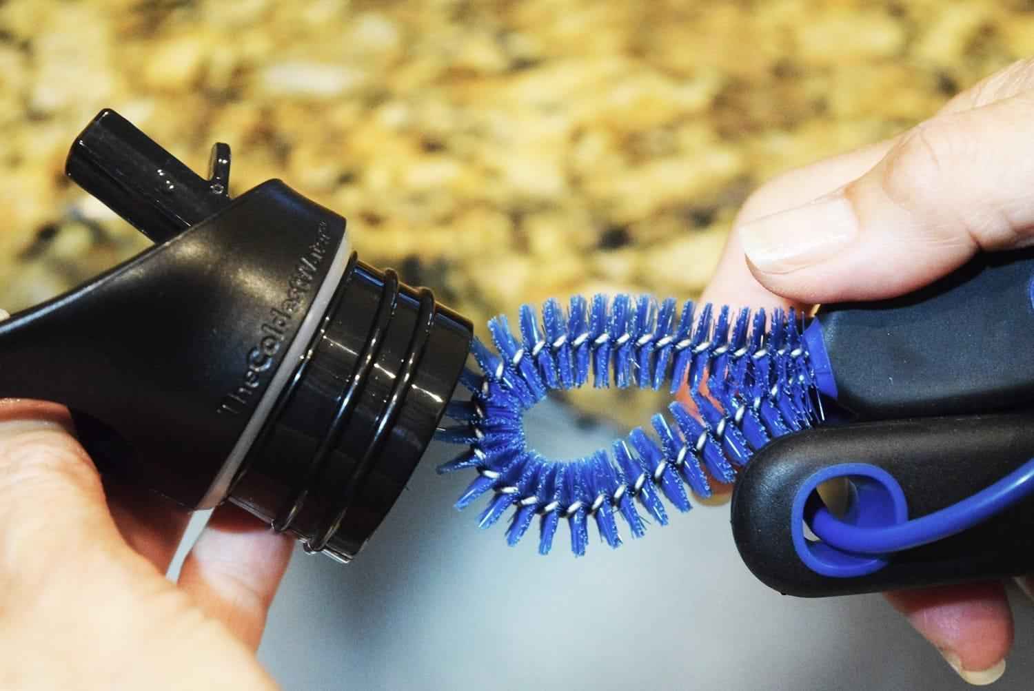 Black and blue grooming brush held by a person with a blurred natural background