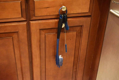 Blue brush and scrubber hanging on a wooden cabinet door