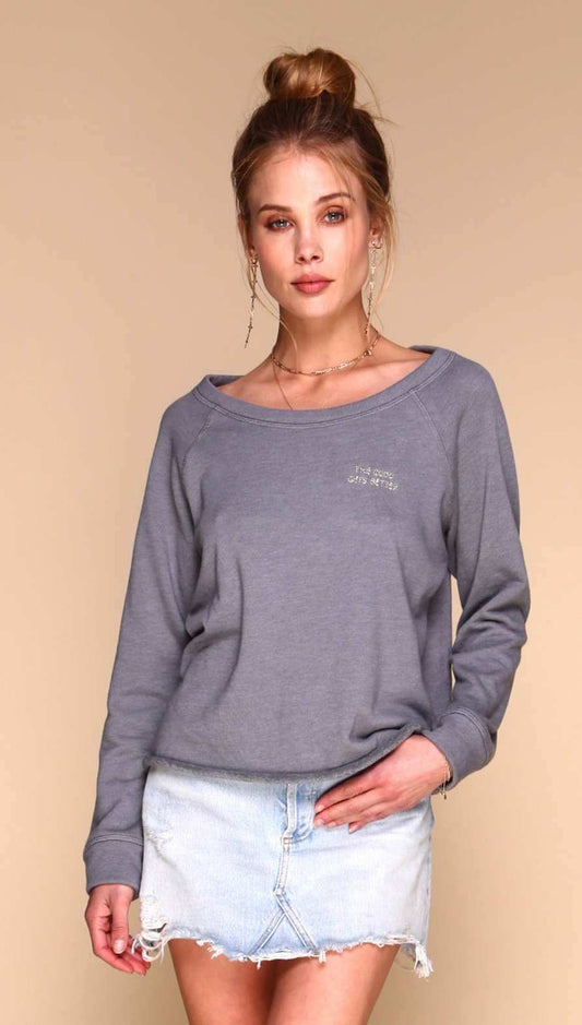 Woman wearing a gray sweatshirt with a logo on a beige background