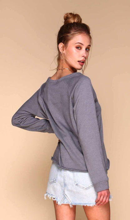 Woman wearing a gray long-sleeve top and denim shorts on a beige background