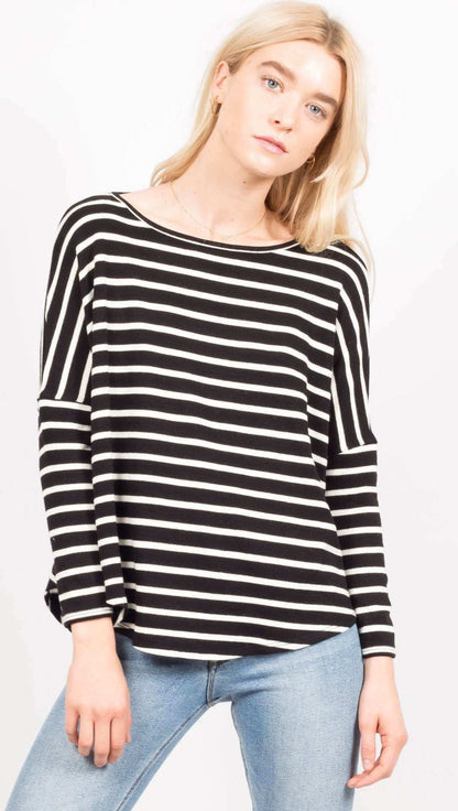 Woman wearing a black and white striped sweater with light blue jeans on a white background