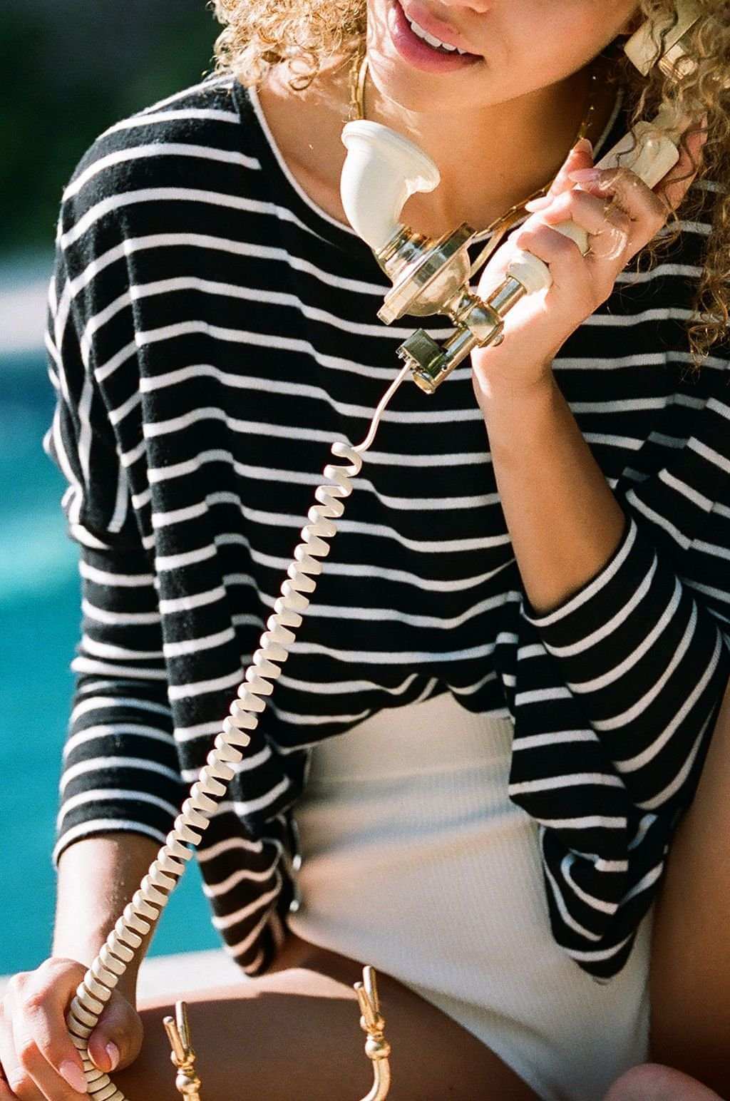 Person in a striped shirt holding a vintage phone with a blurred background