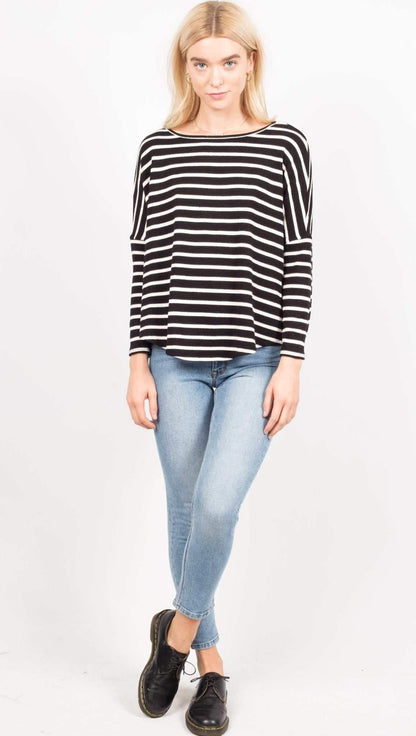 Woman wearing a black and white striped sweater and light blue jeans on a white background