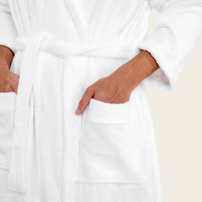Person wearing a white robe with hands in pockets on a neutral background