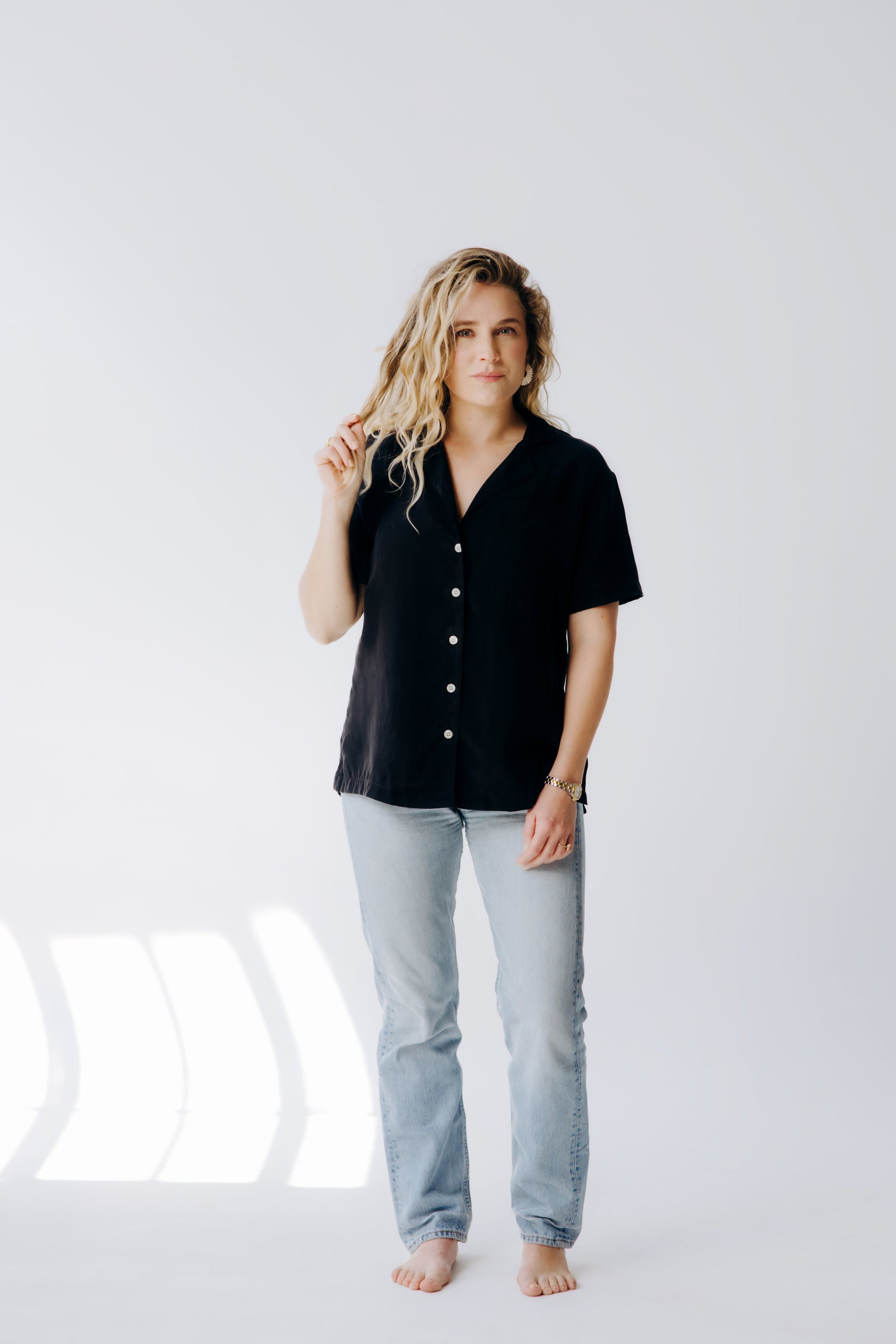 Woman wearing a black shirt and light blue jeans on a white background