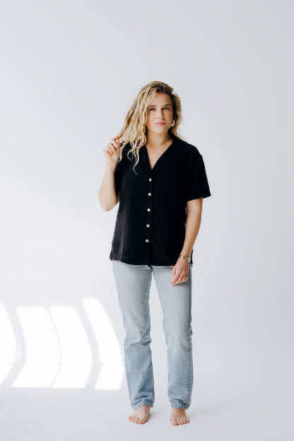 Woman wearing a black shirt and light blue jeans on a white background