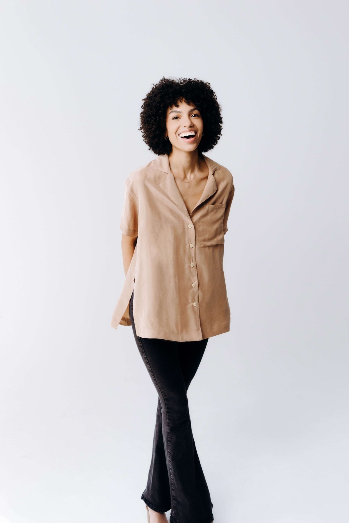 Woman wearing a beige coat and black pants on a white background