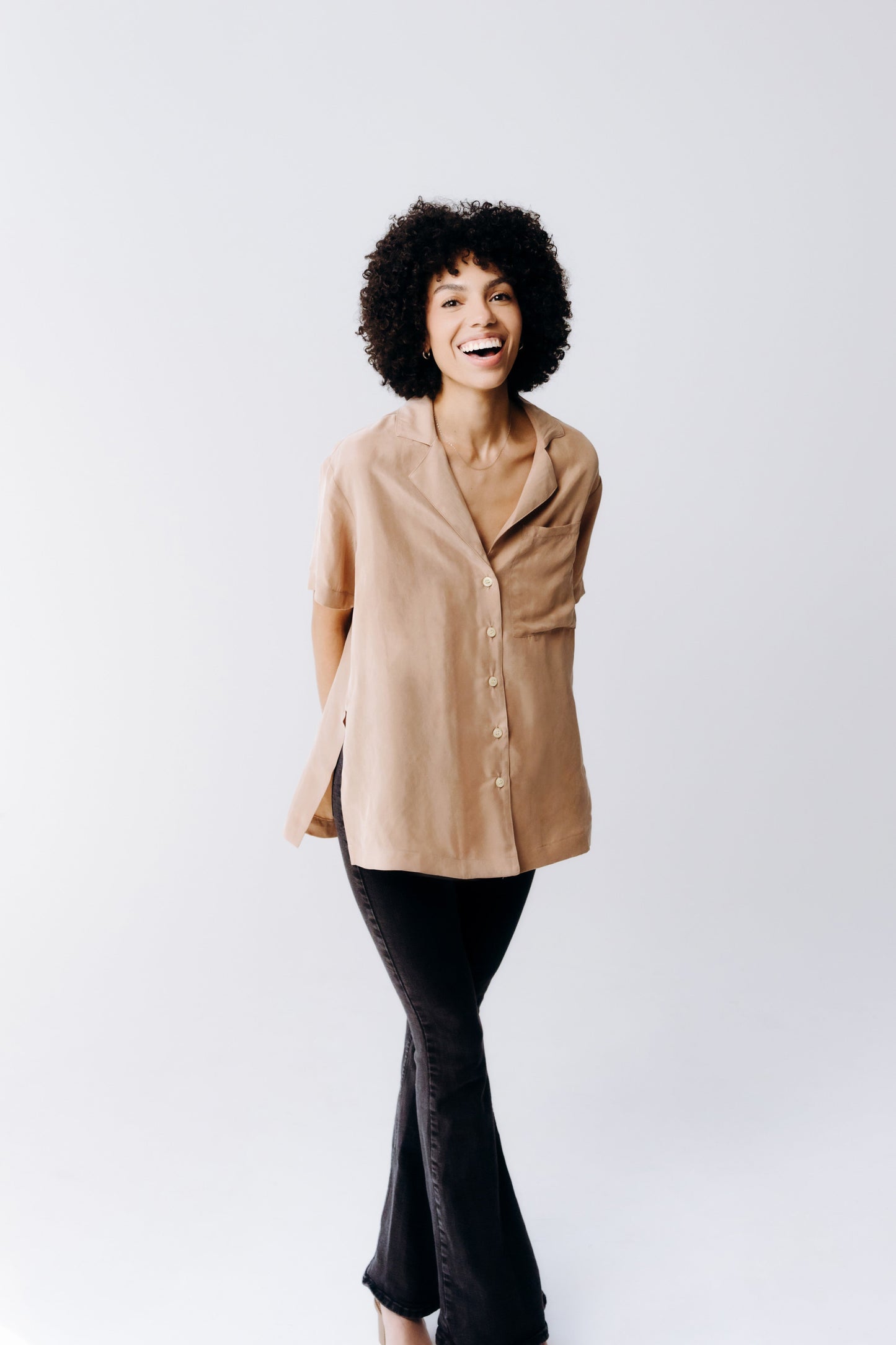 Woman wearing a beige coat and black pants on a white background