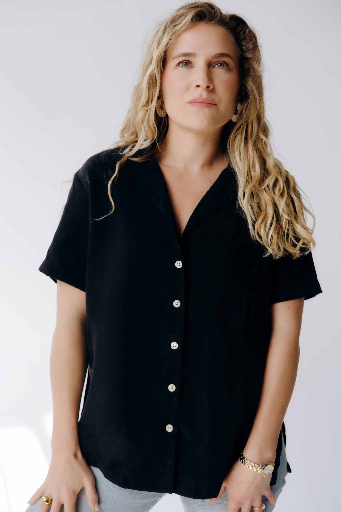 Woman wearing a black button-up shirt against a white background
