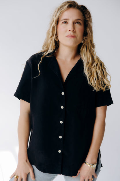 Woman wearing a black button-up shirt against a white background