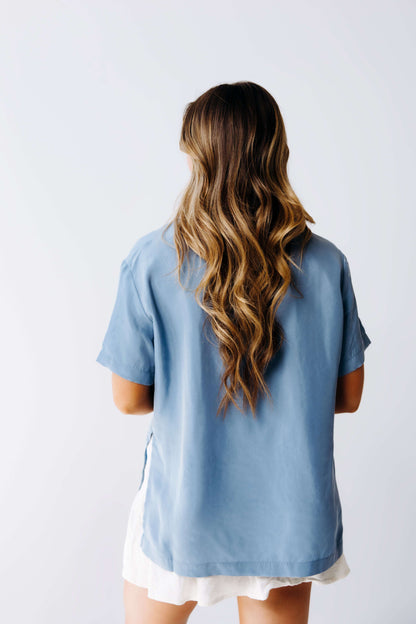 Person wearing a light blue shirt with long hair on a plain background