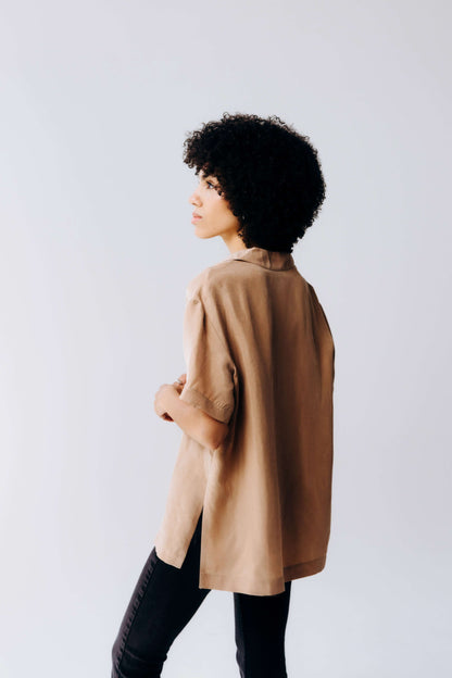 Person wearing a brown coat against a plain background