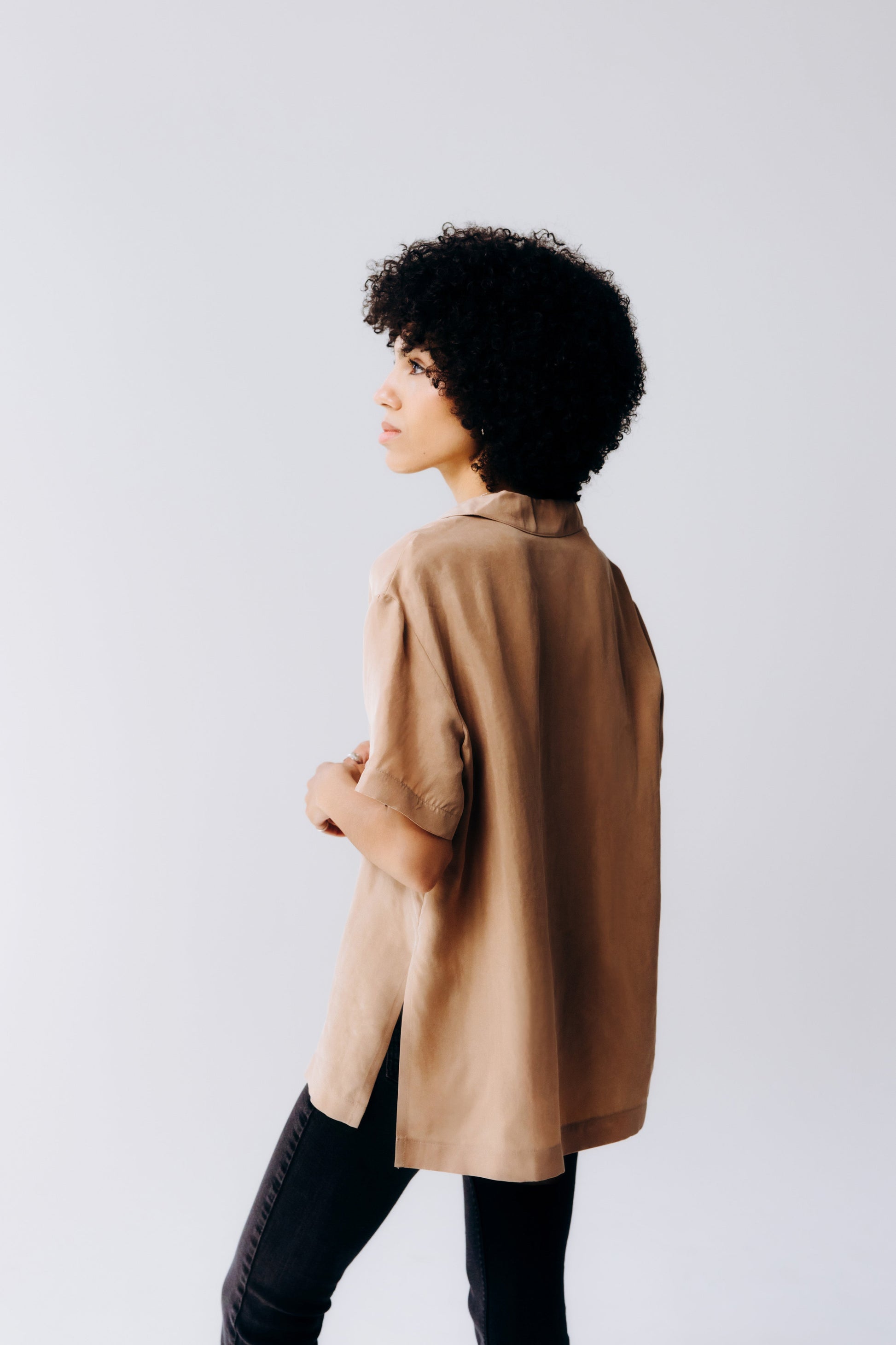 Person wearing a brown coat against a plain background