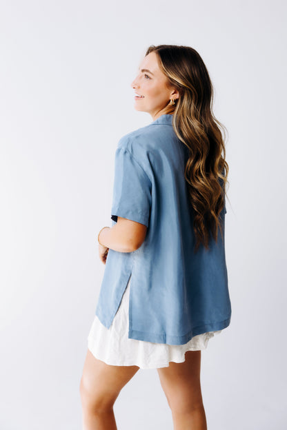 Woman wearing a blue shirt over a white dress against a plain background