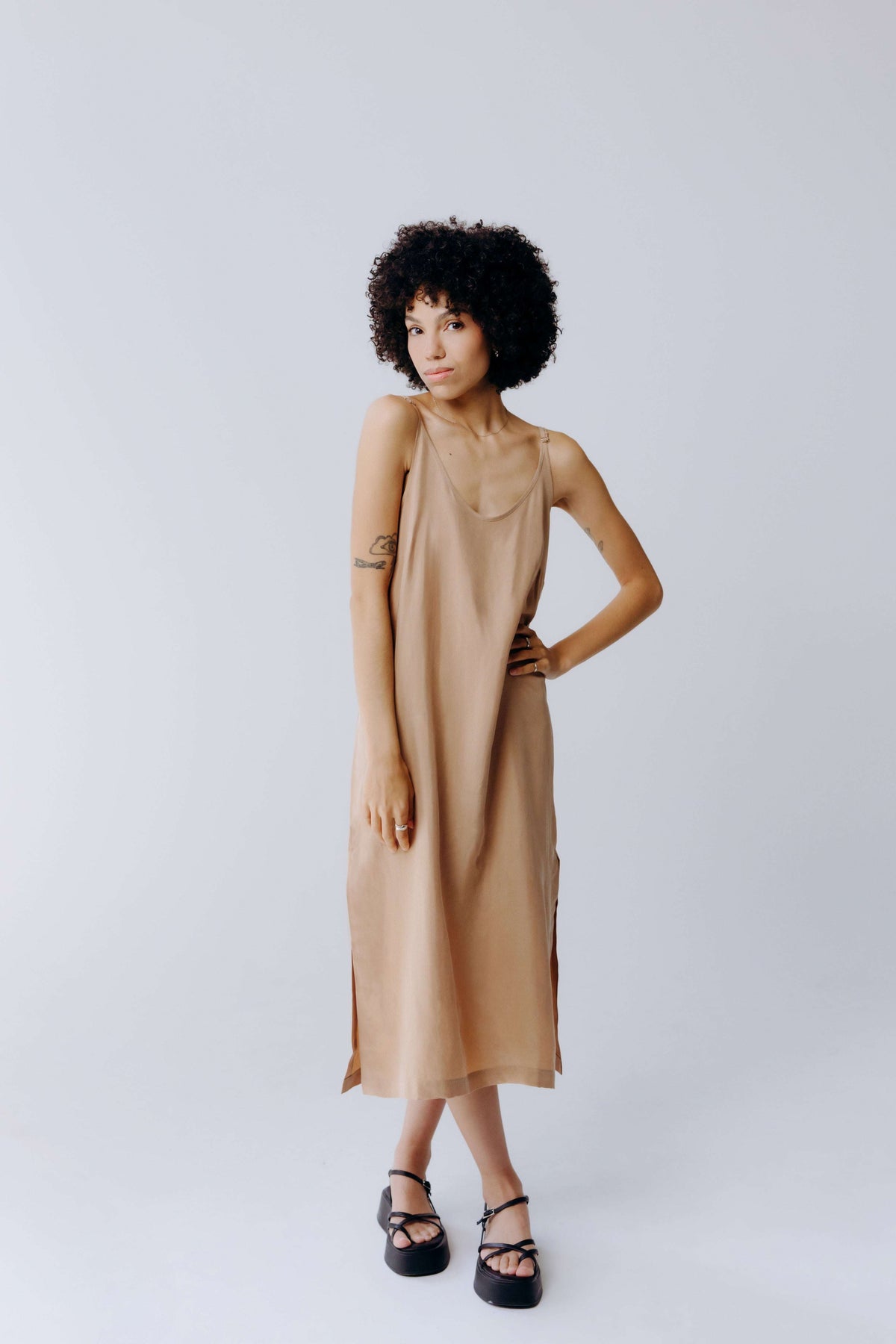 Woman wearing a beige dress against a plain background