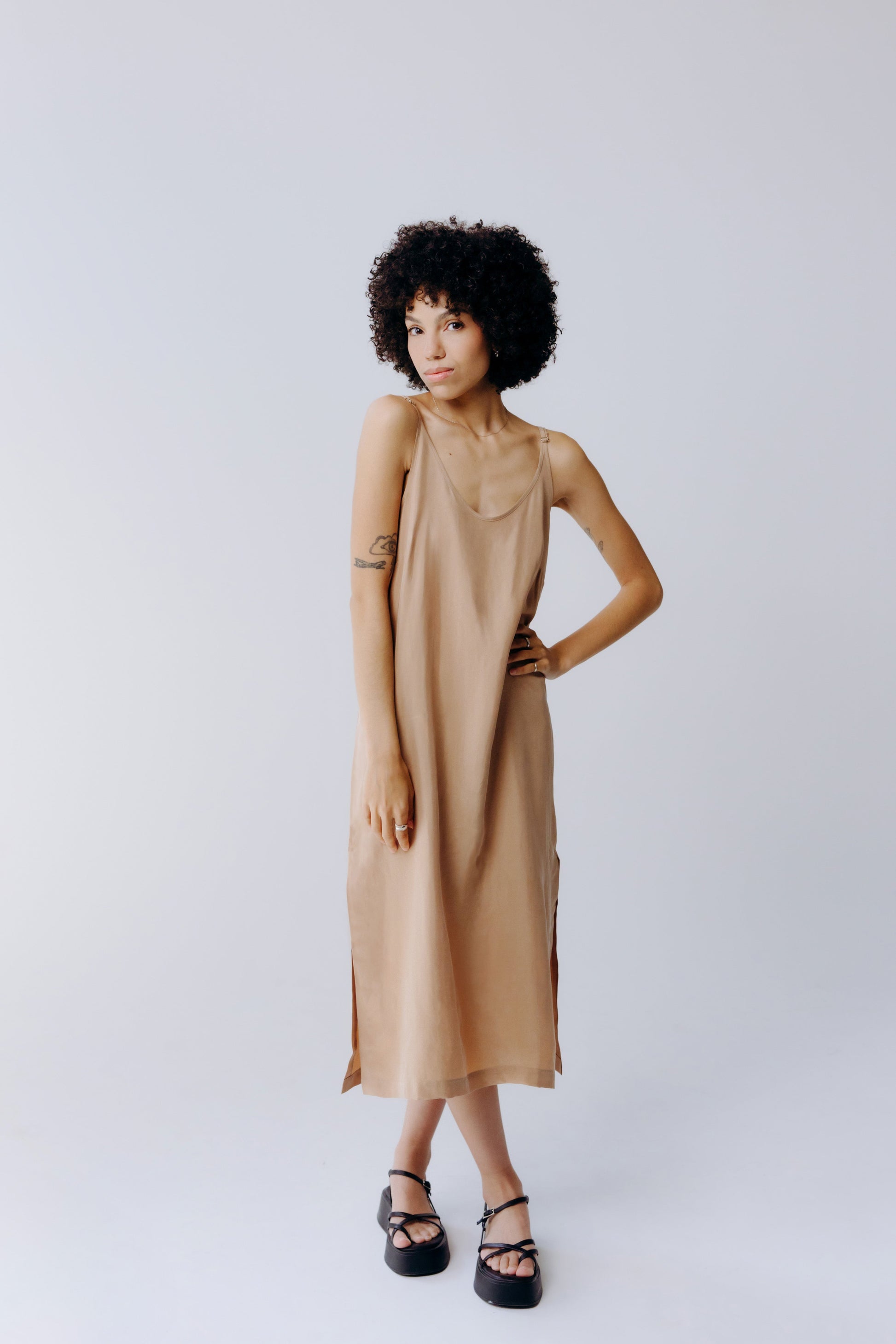 Woman wearing a beige dress against a plain background