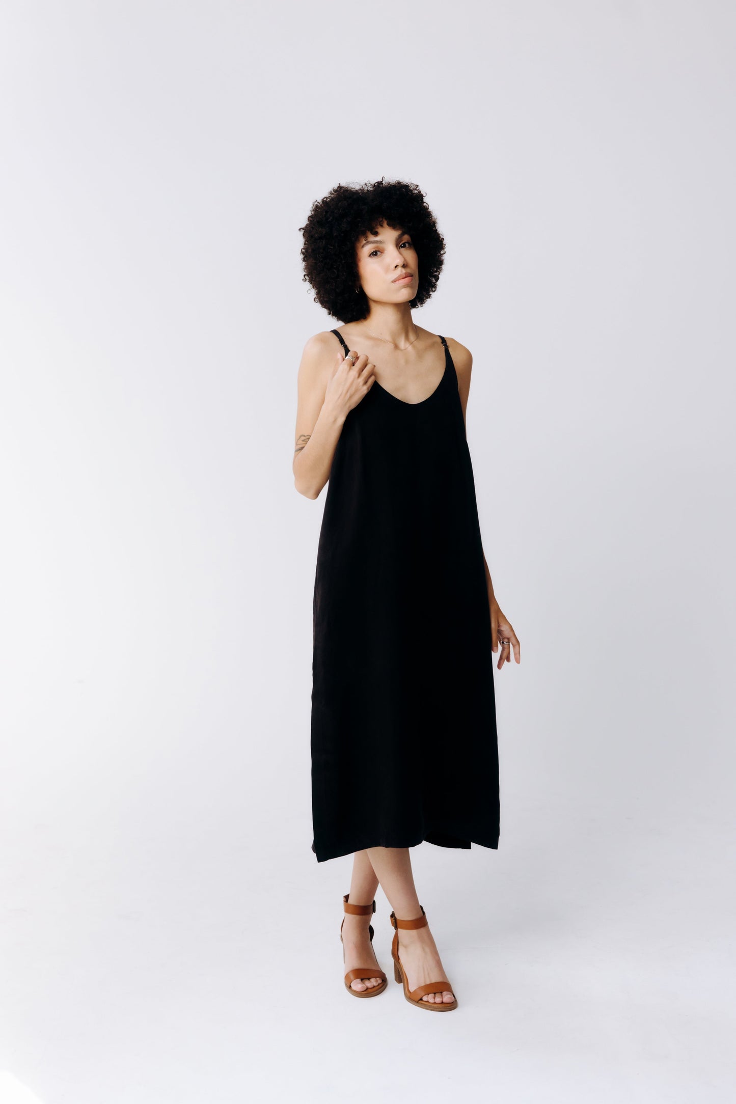 Woman wearing a black slip dress on a white background