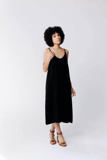 Woman wearing a black slip dress on a white background